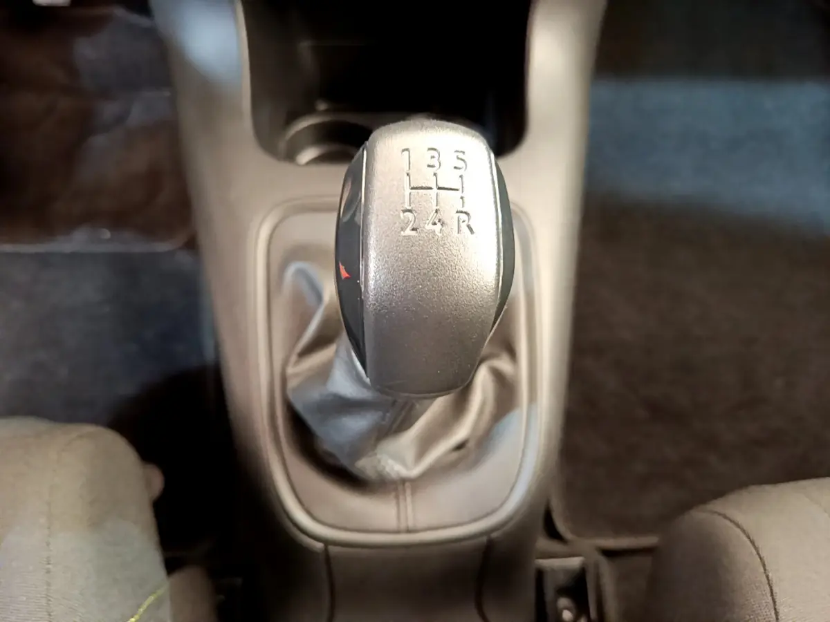 Le levier de vitesses manuel gris de la CITROEN C3 PureTech 82 S&S BVM Graphic vu de dessus, entouré de sièges tissu.