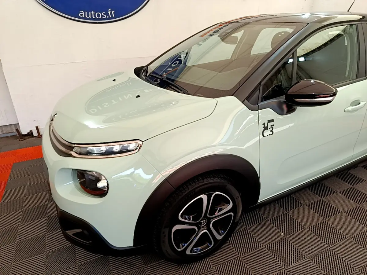 Vue 3/4 avant gauche d'une Citroën C3 vert clair avec jantes noires et logo Graphic sur la portière avant.