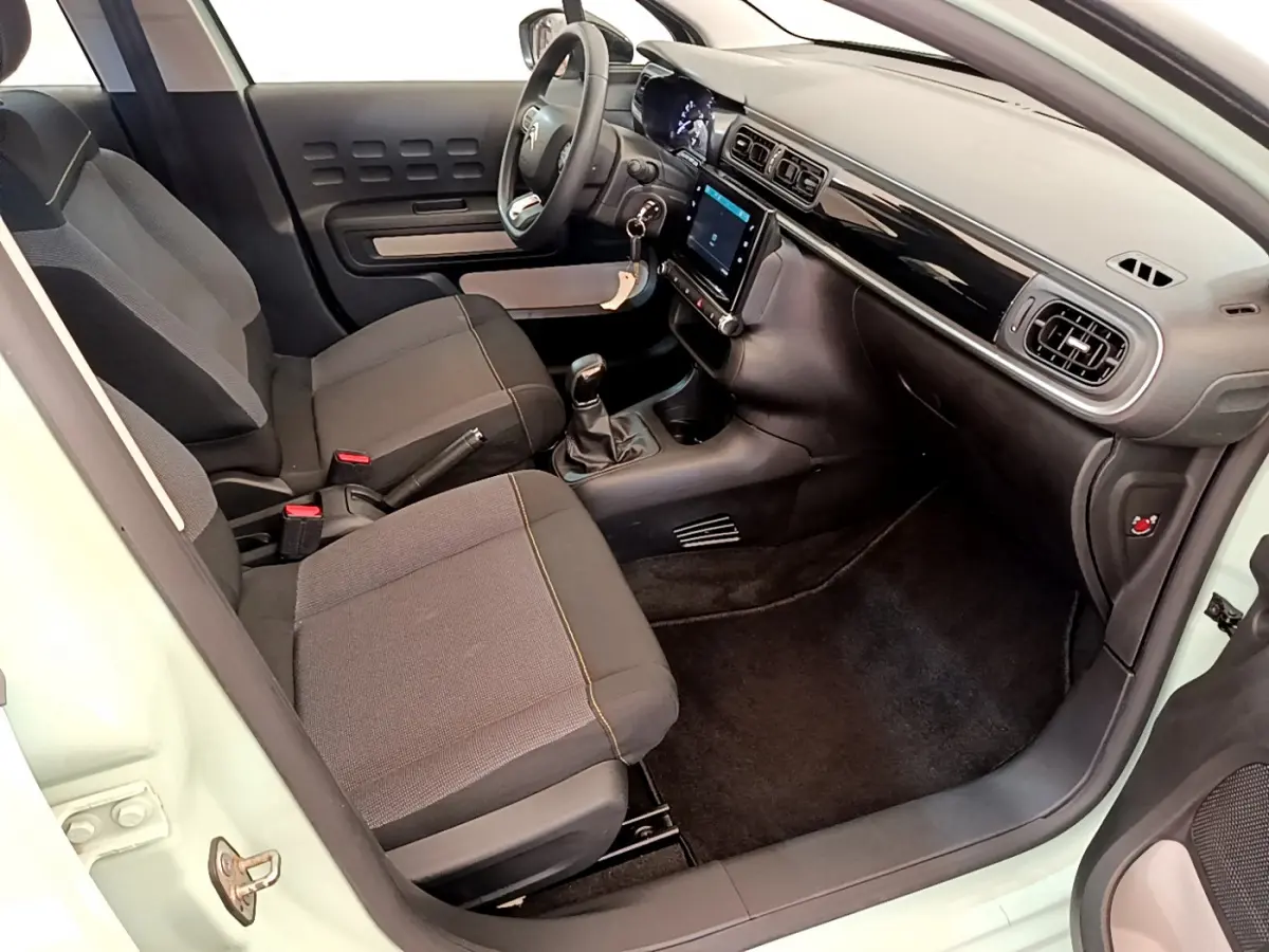 Intérieur avant droit d'une Citroën C3 vert 2019, montrant sièges tissu, volant multifonctions et écran tactile central.