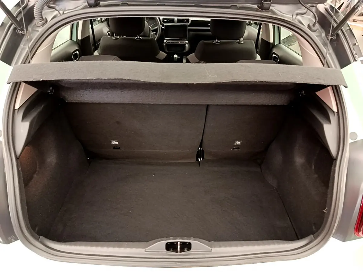 Vue du coffre ouvert d'une Citroën C3 vert 2019, montrant l'intérieur spacieux et la tablette de séparation.