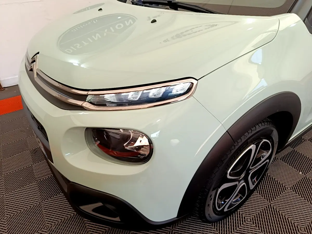 Vue 3/4 avant droit d'une Citroën C3 PureTech 82 S&S BVM Graphic vert clair avec phares LED et jantes stylisées.