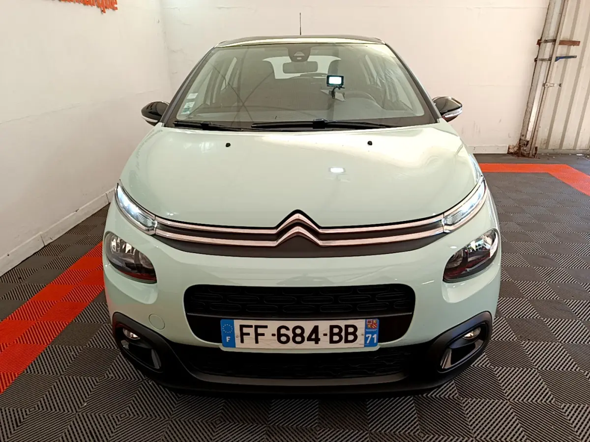 Vue avant d'une Citroën C3 PureTech 82 vert clair avec phares LED et calandre noire dans un garage.