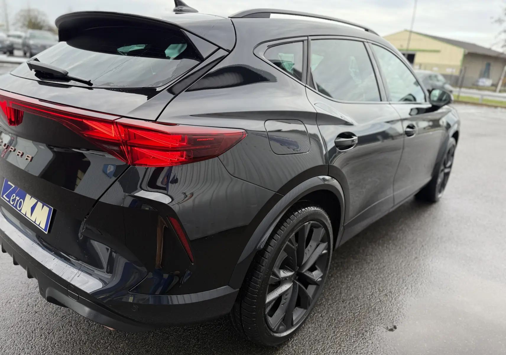 Vue 3/4 arrière droite d’un CUPRA Formentor noir minuit avec feux arrière LED et jantes noires biton.