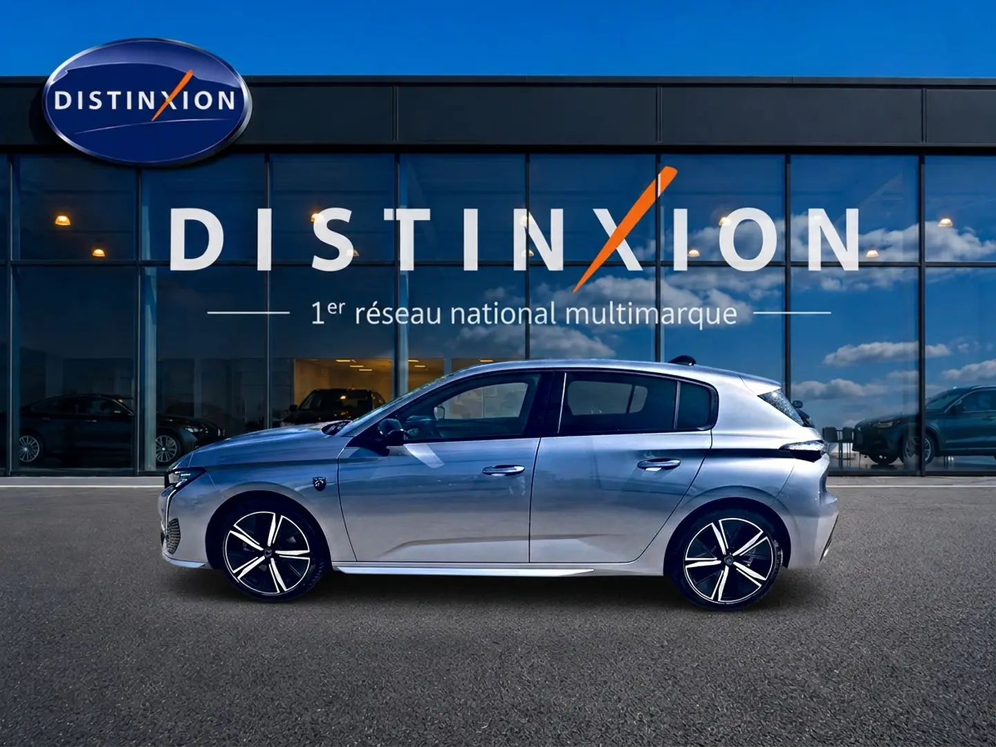 Peugeot 308 gris vue de profil côté gauche, avec jantes alliage distinctives, devant une vitrine Distinxion.