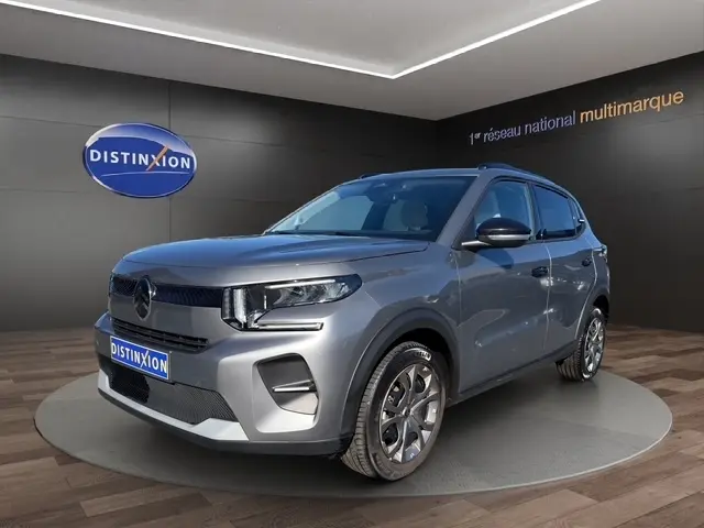 Vue 3/4 avant droite d'une Citroën C3 gris foncé avec jantes alliage et calandre noire distinctive.