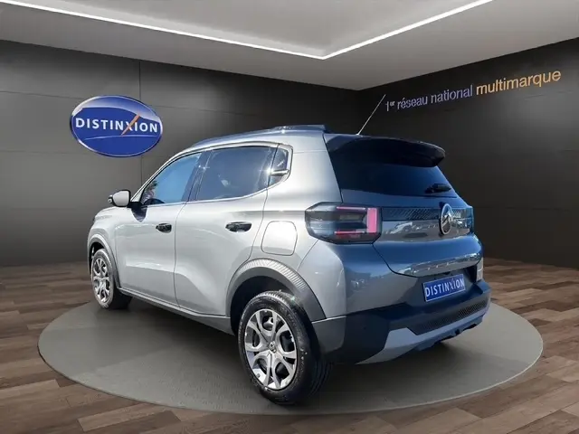 Vue 3/4 arrière droite d'une Citroën C3 gris foncé 2025 avec spoiler de coffre et feux LED distinctifs.
