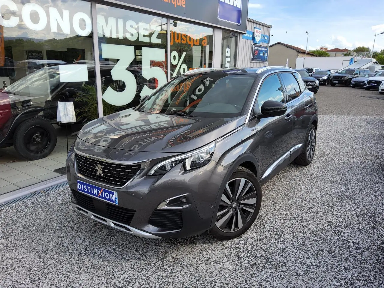 Peugeot 3008 gris métallisé en 3/4 avant droit avec jantes alliage et toit noir sur parking de concession.