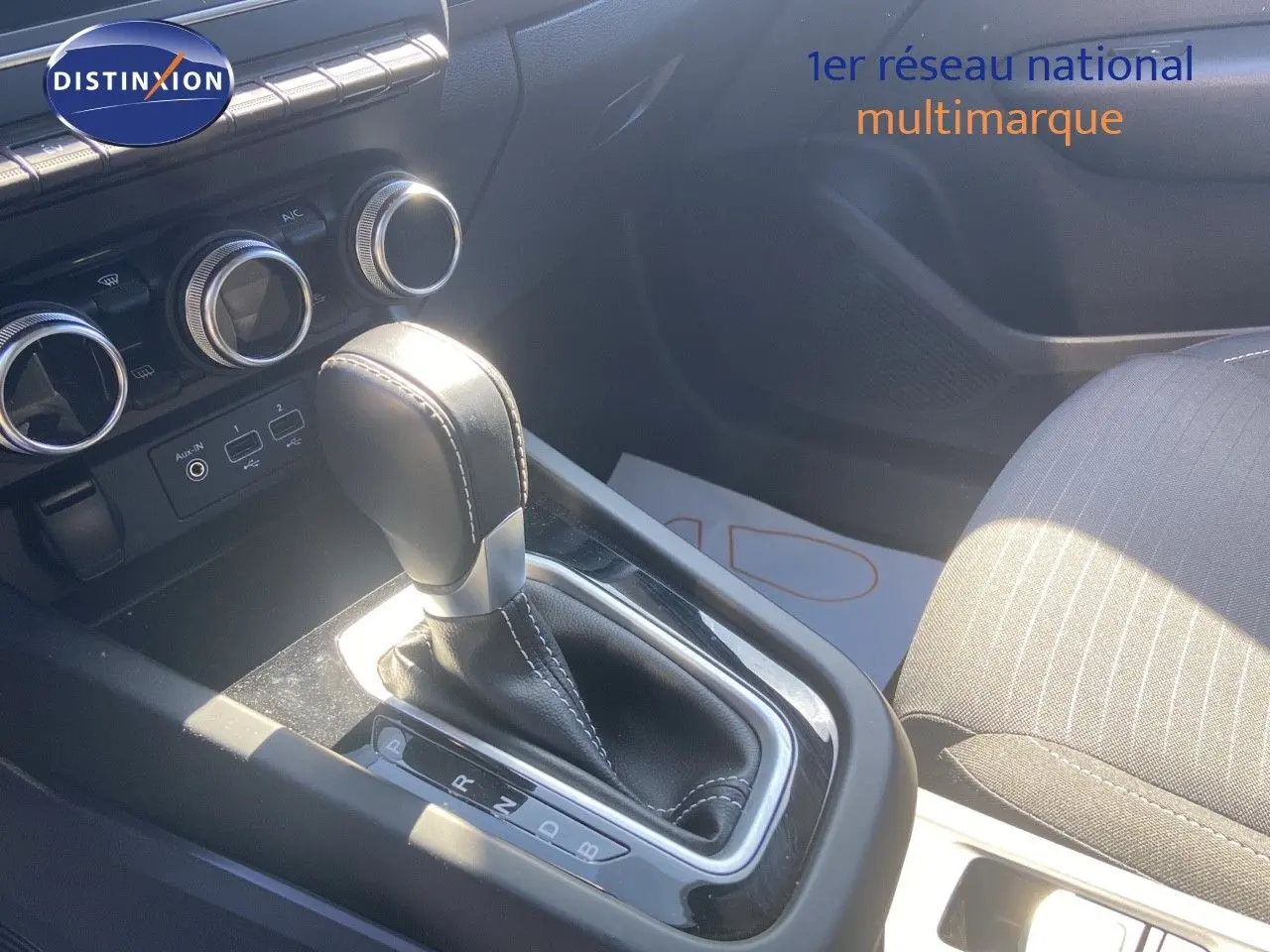 Le levier de vitesse cuir noir de la Renault Arkana hybride 2023, avec commandes de climatisation en arrière-plan.