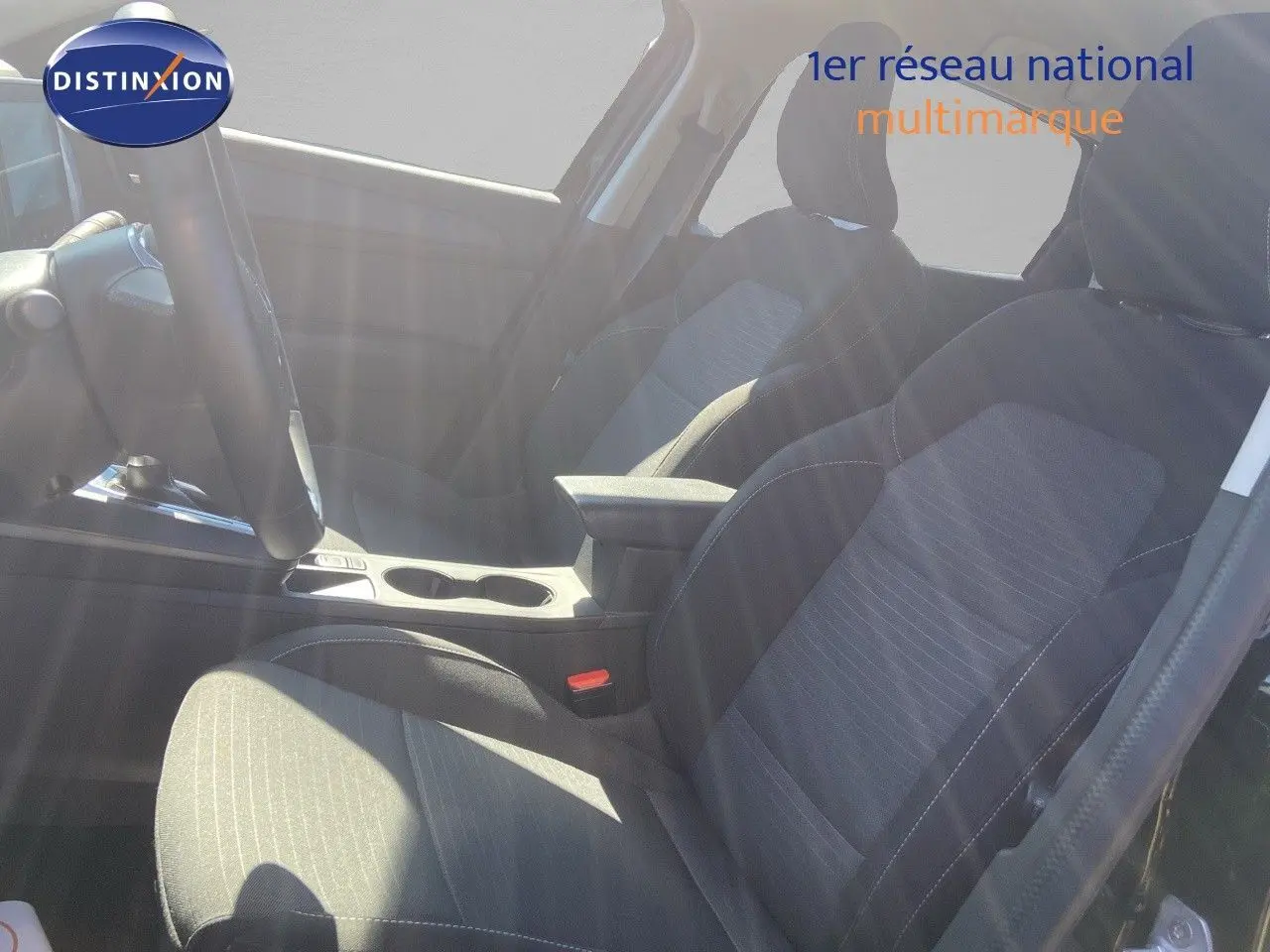 Vue intérieure côté conducteur du Renault Arkana 2023, sièges tissu gris noir avec accoudoir central.