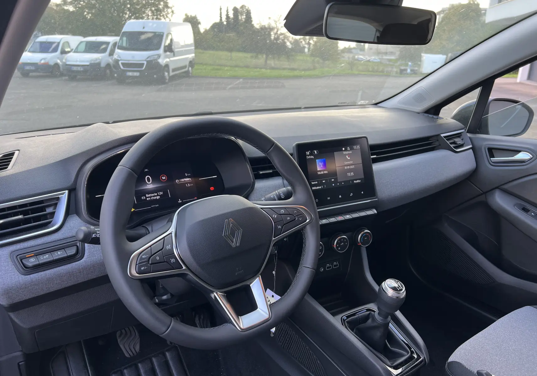 Intérieur avant de la Renault Clio V gris schiste, tableau de bord avec écran tactile 7 pouces et boîte manuelle visible.