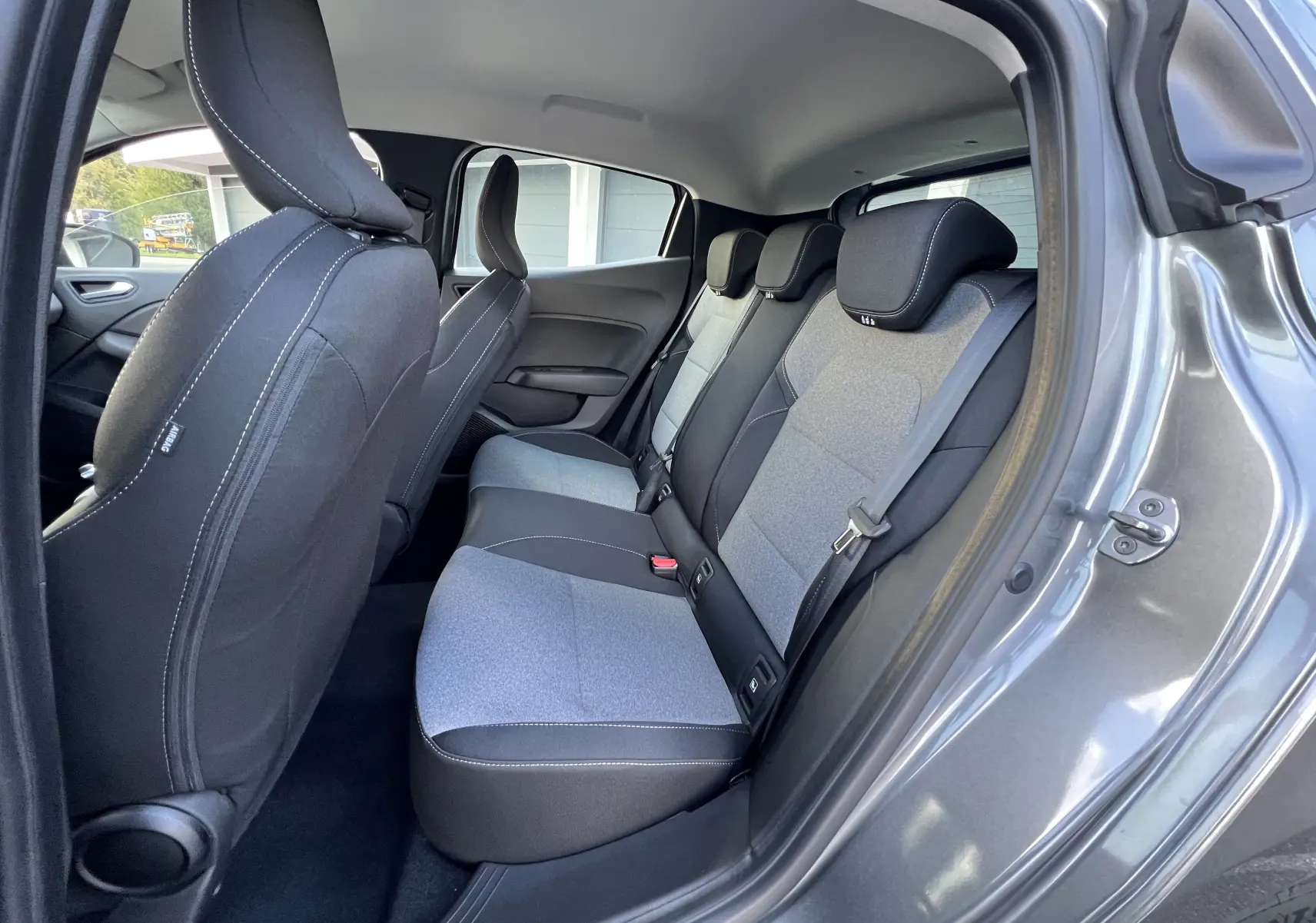 Vue intérieure côté droit sur les sièges arrière gris clair et noir de la Renault Clio V gris schiste avec portière ouverte.