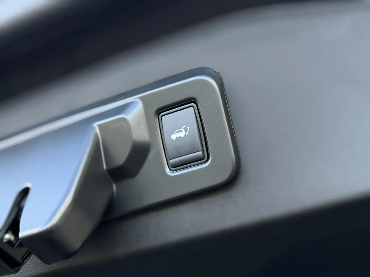 Bouton d'ouverture électrique du hayon sur le panneau intérieur d'un Renault Espace VI noir étoilé.