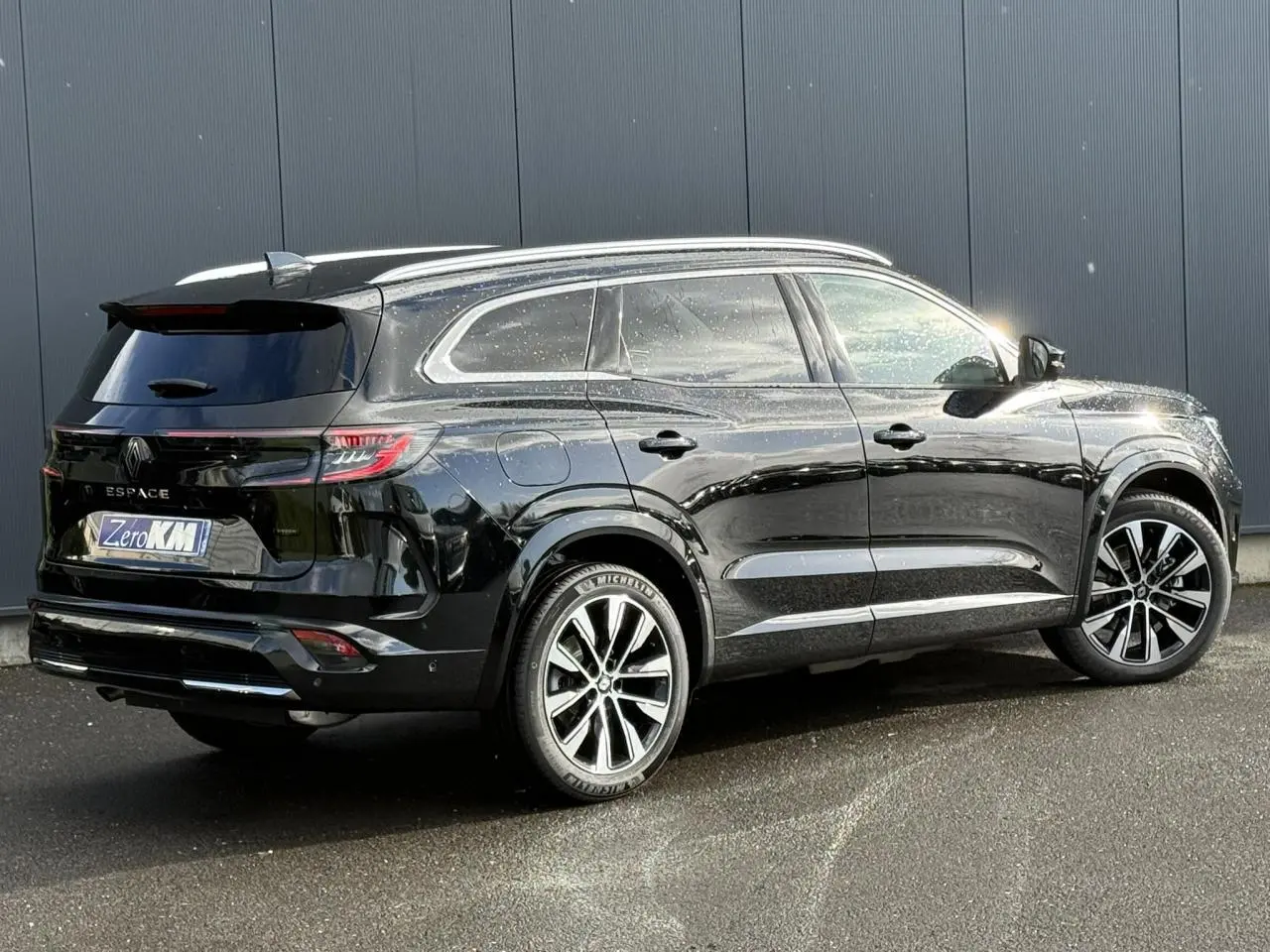 Renault Espace VI noir étoilé en 3/4 arrière droit, avec jantes alliage noires et toit panoramique visible.