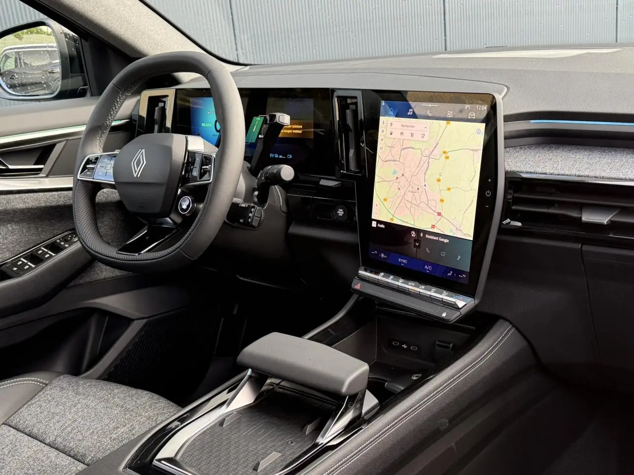 Intérieur côté conducteur du Renault Espace VI hybride noir, avec grand écran tactile vertical et volant multifonction.