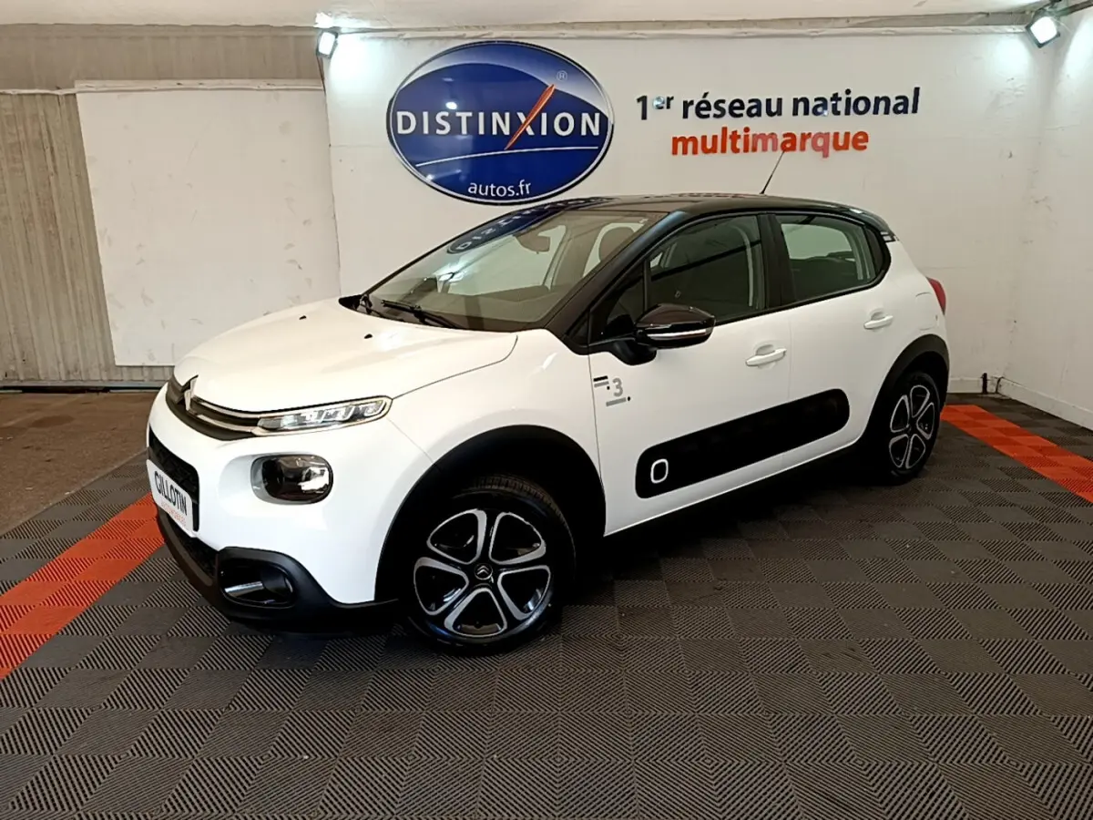 Citroën C3 PureTech 82 blanc vue 3/4 avant droit avec toit noir et protections latérales noires.