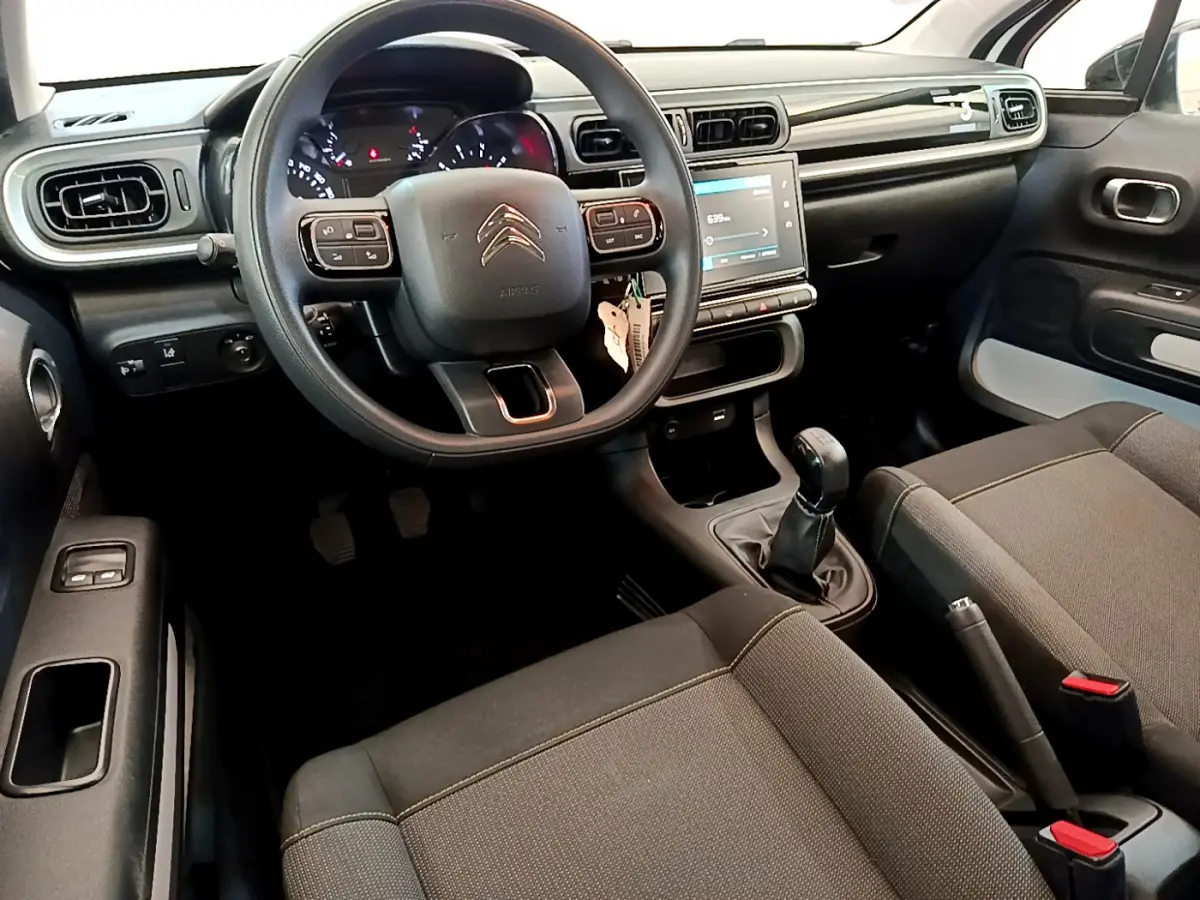 Vue intérieure avant du Citroën C3 2019 PureTech 82 S&S BVM Graphic, tableau de bord noir avec écran tactile et volant multifonctions.