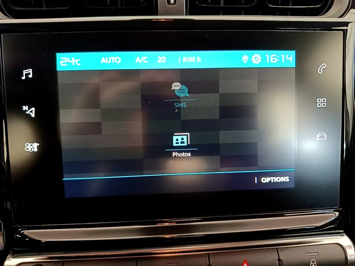 Écran tactile central du tableau de bord de la Citroën C3 blanche, affichant les options SMS et photos.