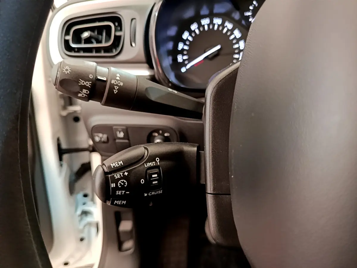 Gros plan sur la commande de régulateur de vitesse à gauche du volant d'une Citroën C3 blanche de 2019.