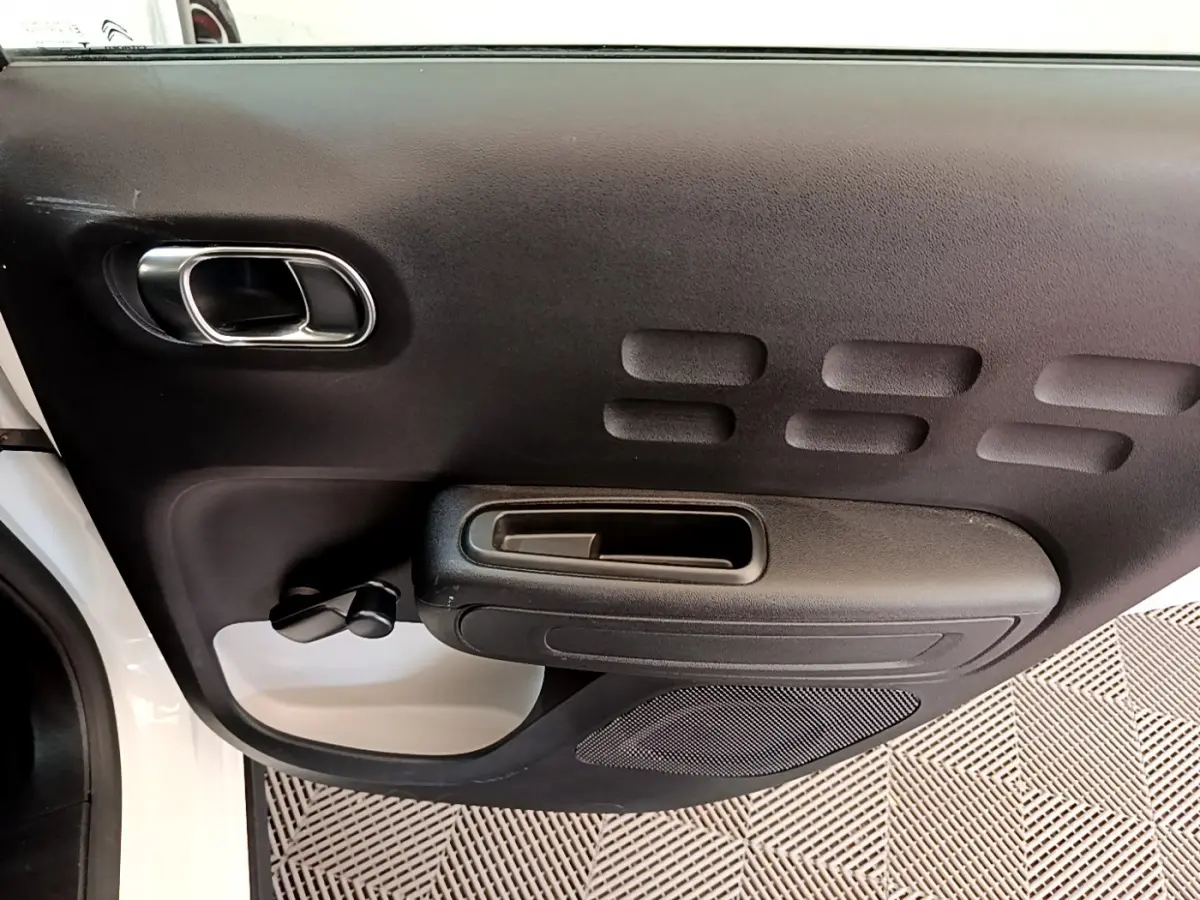 Vue intérieure côté gauche de la porte avant noire avec poignée chromée d'une Citroën C3 blanche 2019.