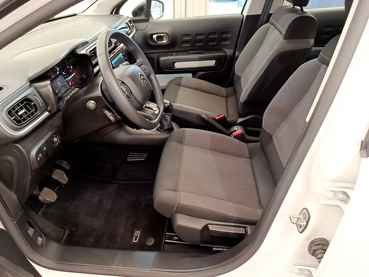 Intérieur avant droit de la Citroën C3 blanche 2019, sièges tissu gris et tableau de bord avec écran tactile.