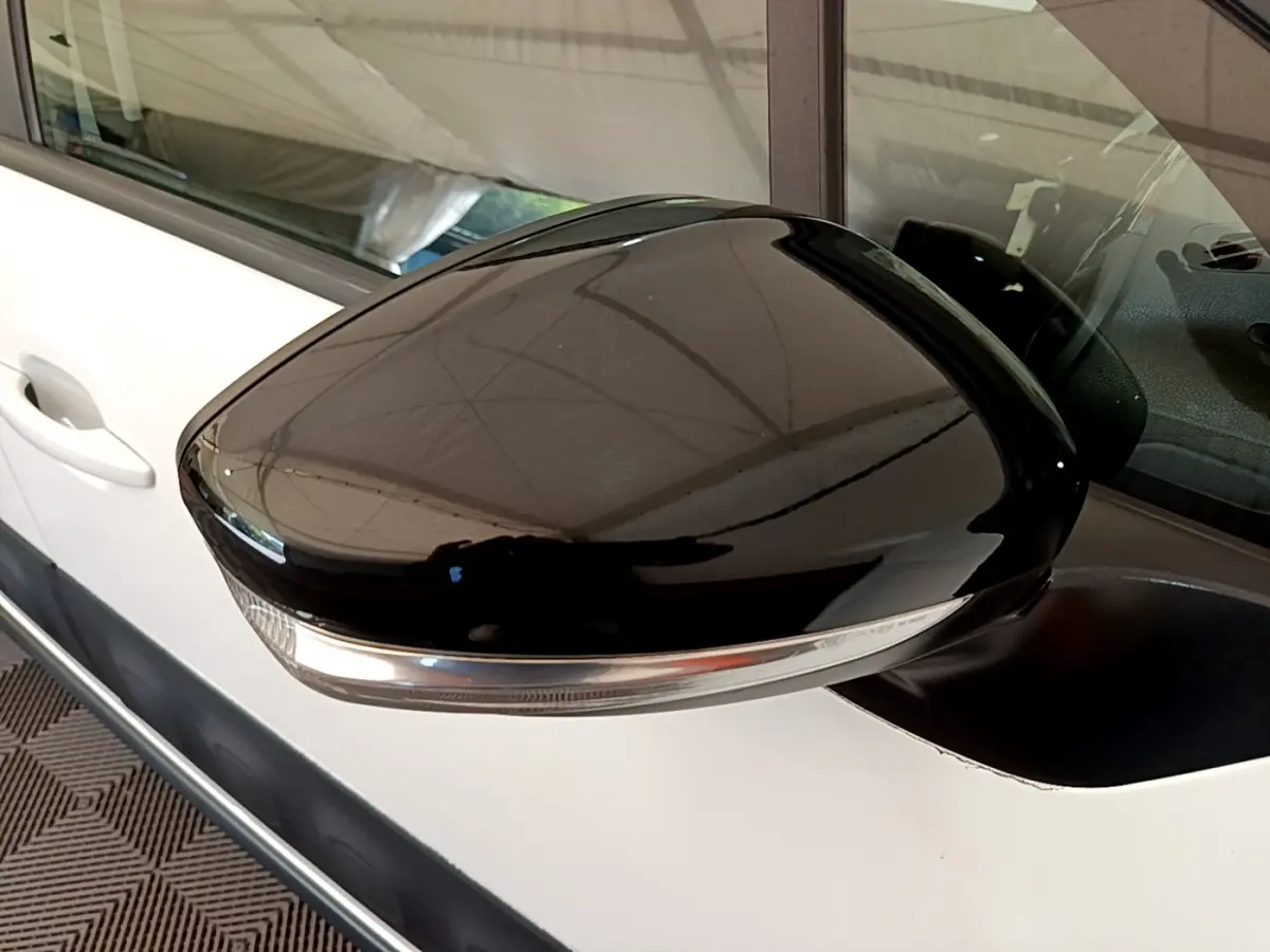 Rétroviseur noir brillant côté gauche d'une Citroën C3 blanche 2019, avec clignotant intégré visible.