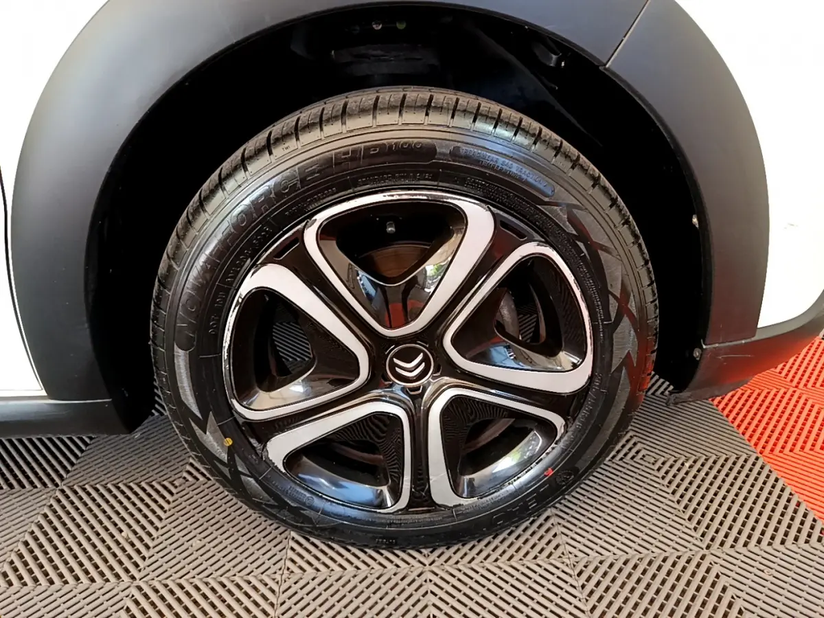 Gros plan sur la roue avant droite noire et chrome d'une Citroën C3 blanche 2019 avec logo Citroën central.