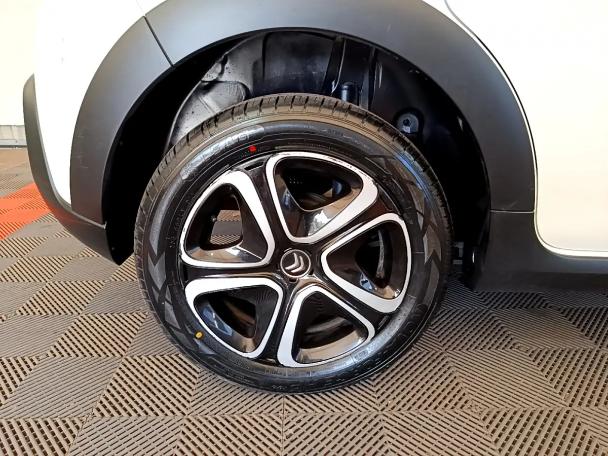 Gros plan sur la roue avant droite d'une Citroën C3 blanche, mettant en valeur la jante noire et argentée au design moderne.