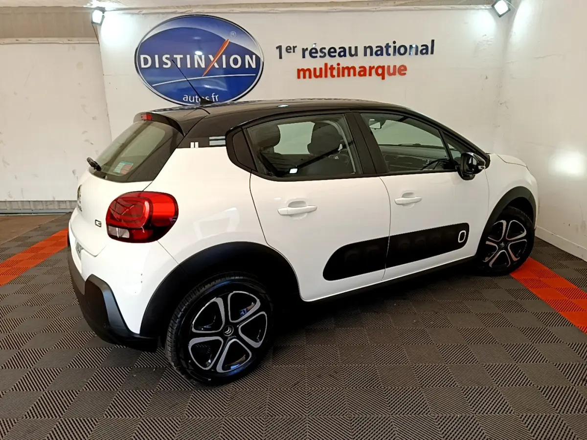 Citroën C3 PureTech 82 blanc vue 3/4 arrière côté droit avec toit noir et protections latérales noires.