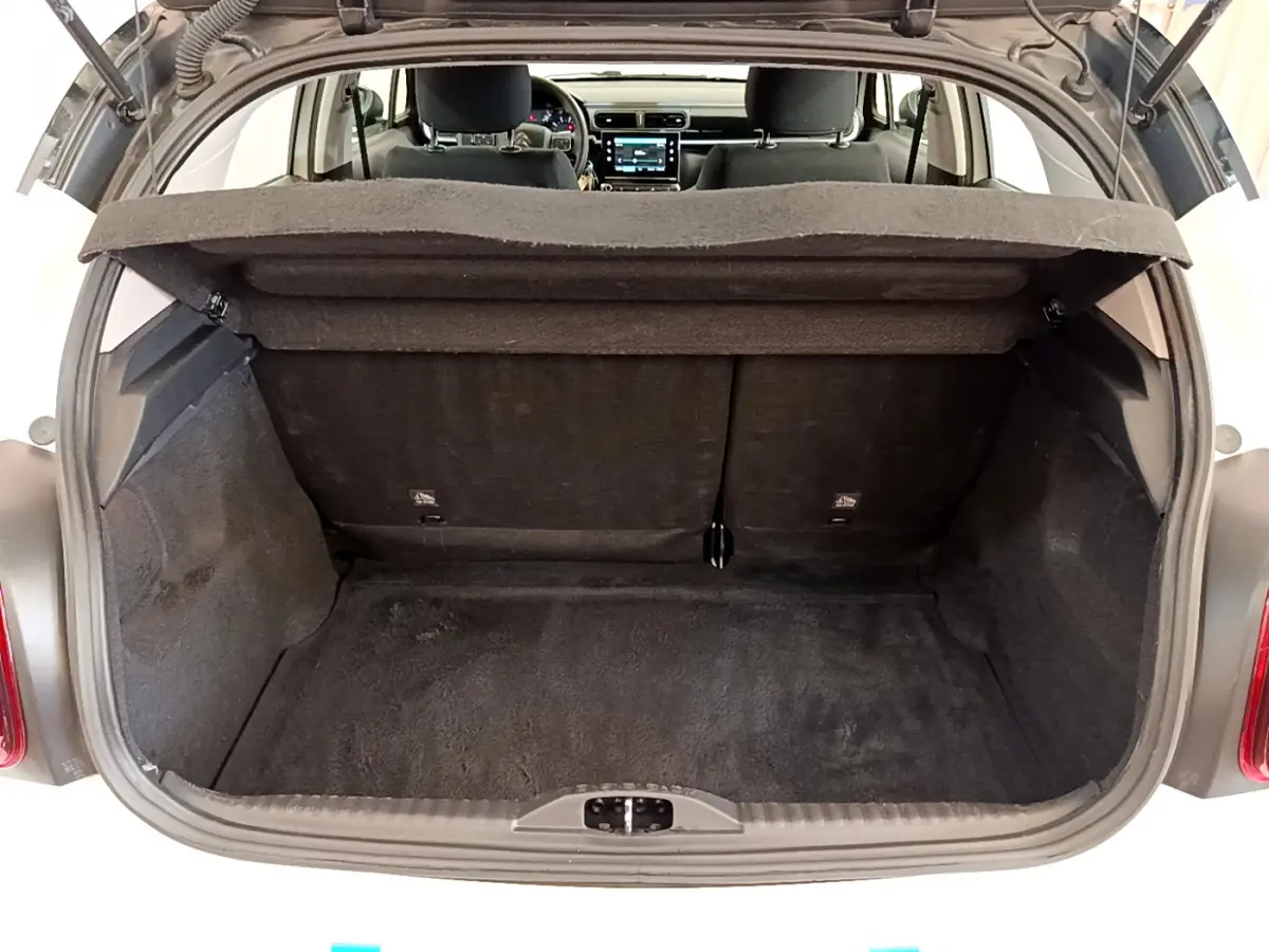 Coffre ouvert vu de l'arrière d'une Citroën C3 blanche, montrant l'espace de chargement et l'intérieur noir.