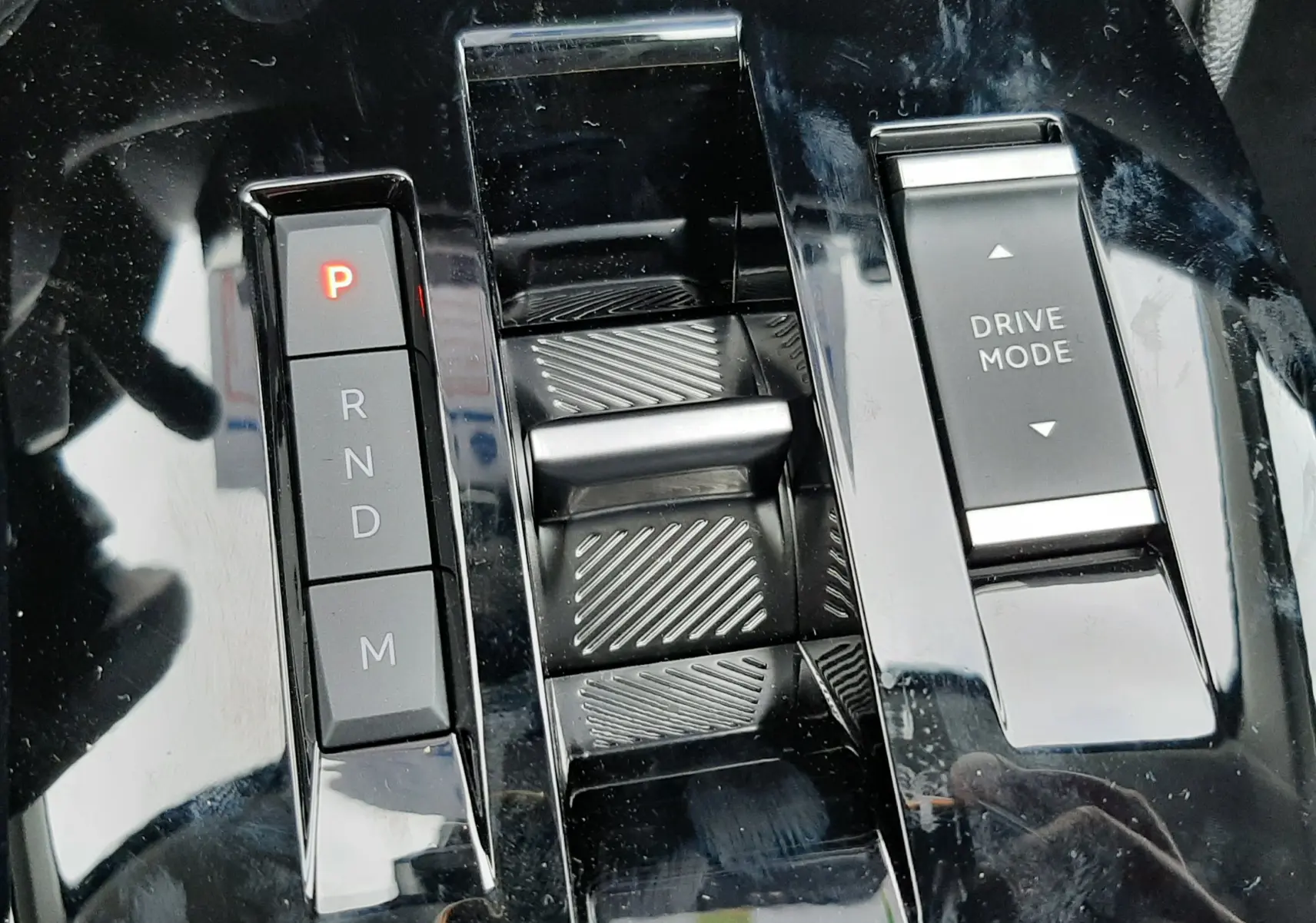 Gros plan sur la console centrale noire brillante de la Citroën C4 hybride 2025 avec commandes de boîte auto et mode de conduite.