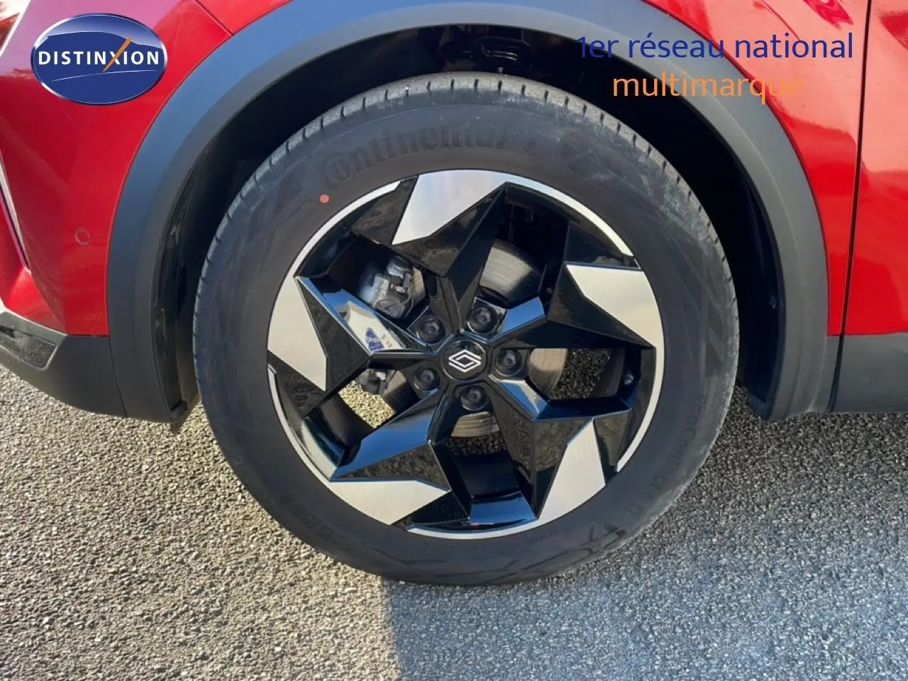 Gros plan sur la roue avant gauche du Renault Captur rouge Désir Métal avec jante noire et argentée au design moderne.