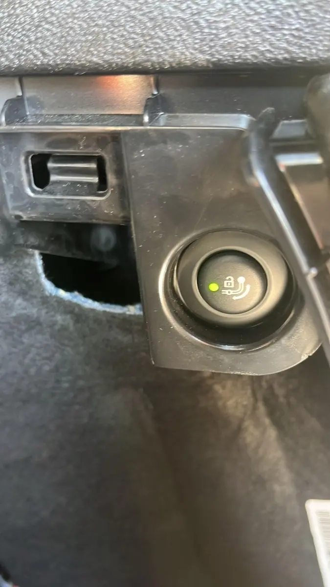 Gros plan sur bouton de déverrouillage électrique du coffre dans le coffre d'un BMW X3 blanc 2023.