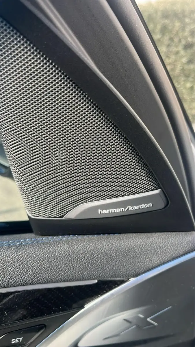 Gros plan sur l'enceinte Harman/Kardon côté gauche dans l'habitacle noir du BMW X3 blanc xDrive30d 2023.