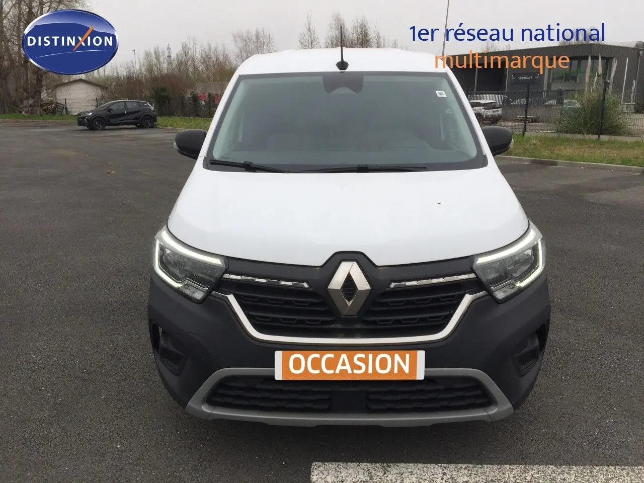 Vue de face du Renault Kangoo Extra blanc 2023 avec calandre noire et feux LED allumés sur parking.