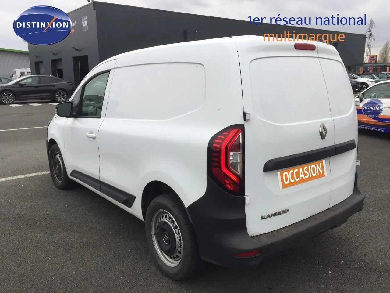 Vue 3/4 arrière droite d’un Renault Kangoo Extra blanc de 2023 avec feux arrière LED et marquage « occasion » sur la porte arrière.
