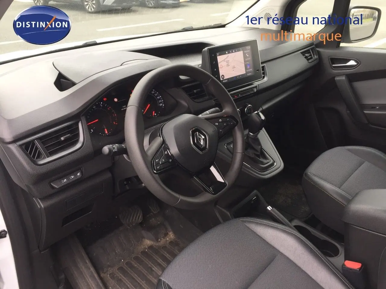 Vue intérieure côté conducteur du Renault Kangoo blanc 2023, avec tableau de bord moderne et écran tactile central.