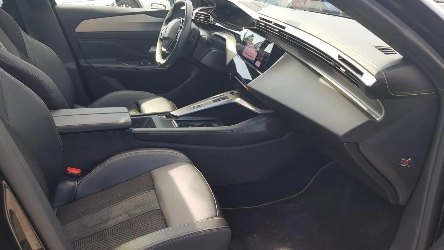 Intérieur noir du Peugeot 308 SW PHEV 225 GT vu côté passager, avec console centrale et volant cuir.