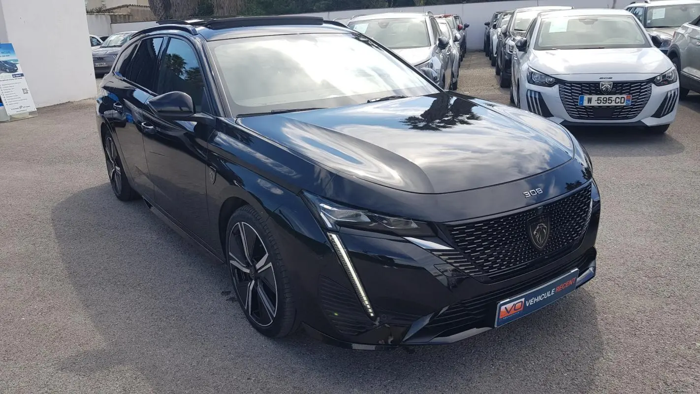 Peugeot 308 SW PHEV noir vue 3/4 avant droit, avec jantes alliage 18 pouces et barres de toit visibles.