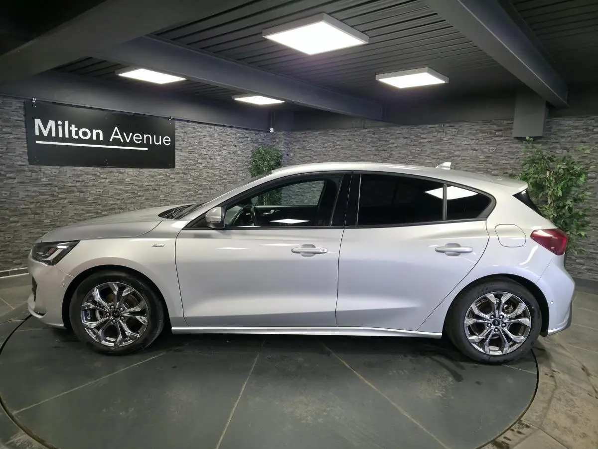 Vue de profil côté gauche d'une Ford Focus 2024 gris lunaire avec jantes alliage 17'' et vitres surteintées.