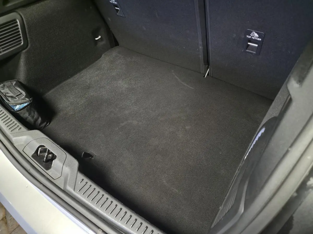 Vue plongeante sur le coffre spacieux et propre de la Ford Focus gris lunaire, avec tapis noir et fixation Top Tether visible.