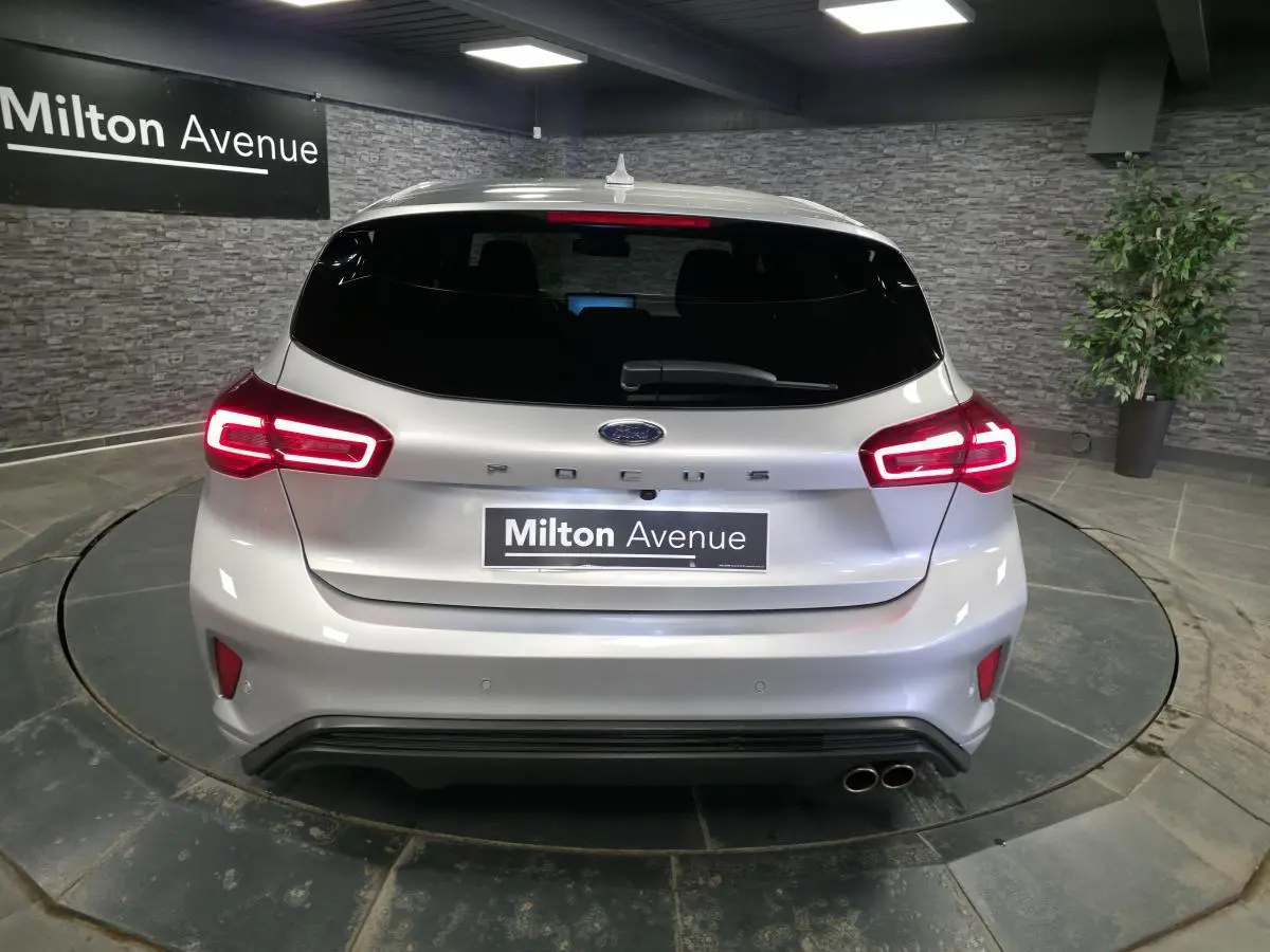 Vue arrière d'une Ford Focus gris lunaire 2024 avec feux LED allumés et double sortie d'échappement sport.