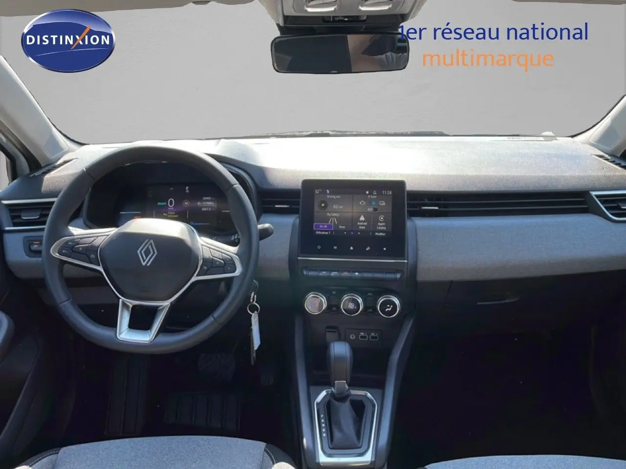 Intérieur de la Renault Clio hybride 2025 vu de face, tableau de bord moderne avec écran tactile et volant multifonction noir.