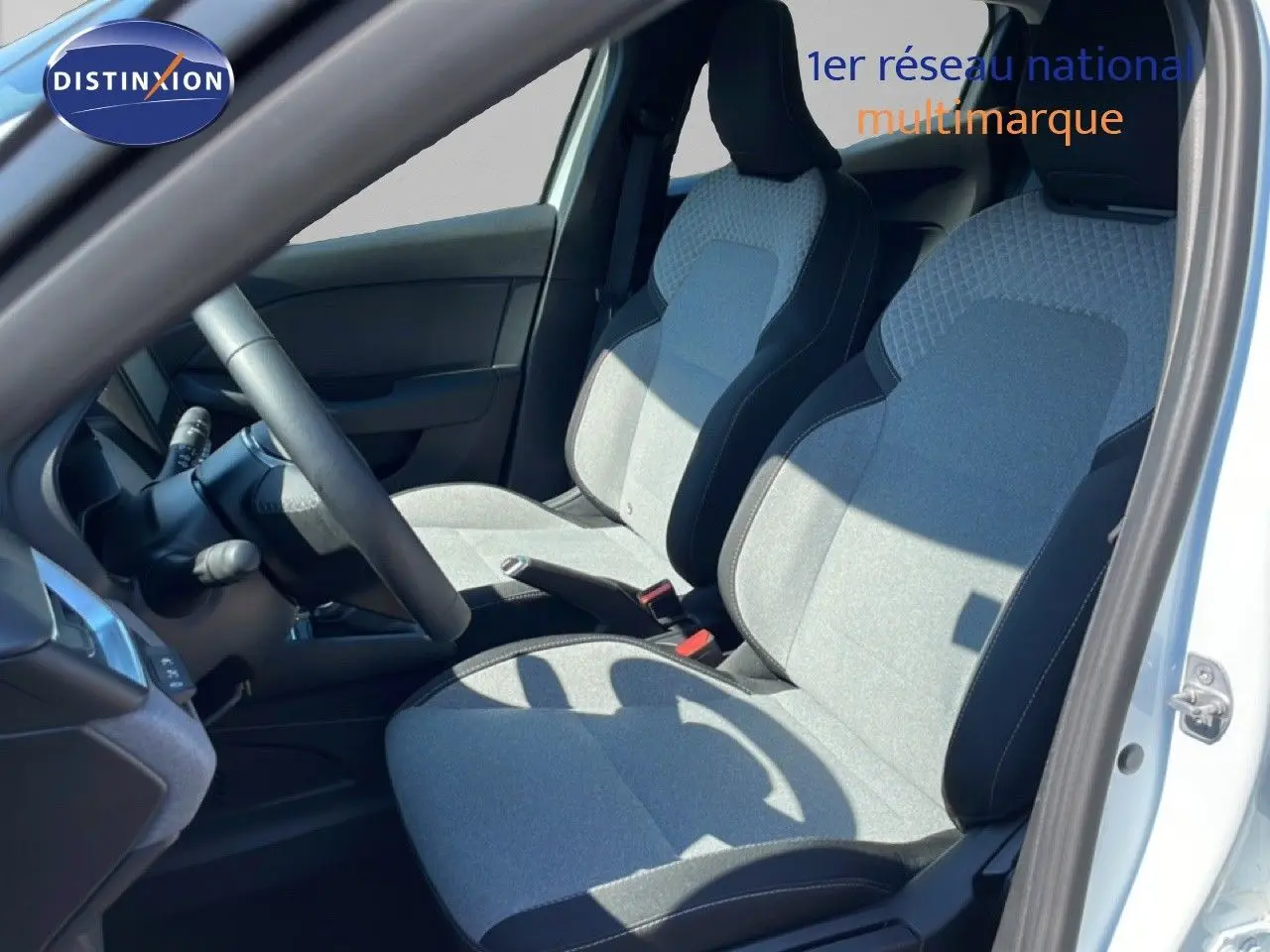 Vue intérieure côté conducteur de la Renault Clio blanche glacier 2025, sièges tissu gris clair avec contours noirs.