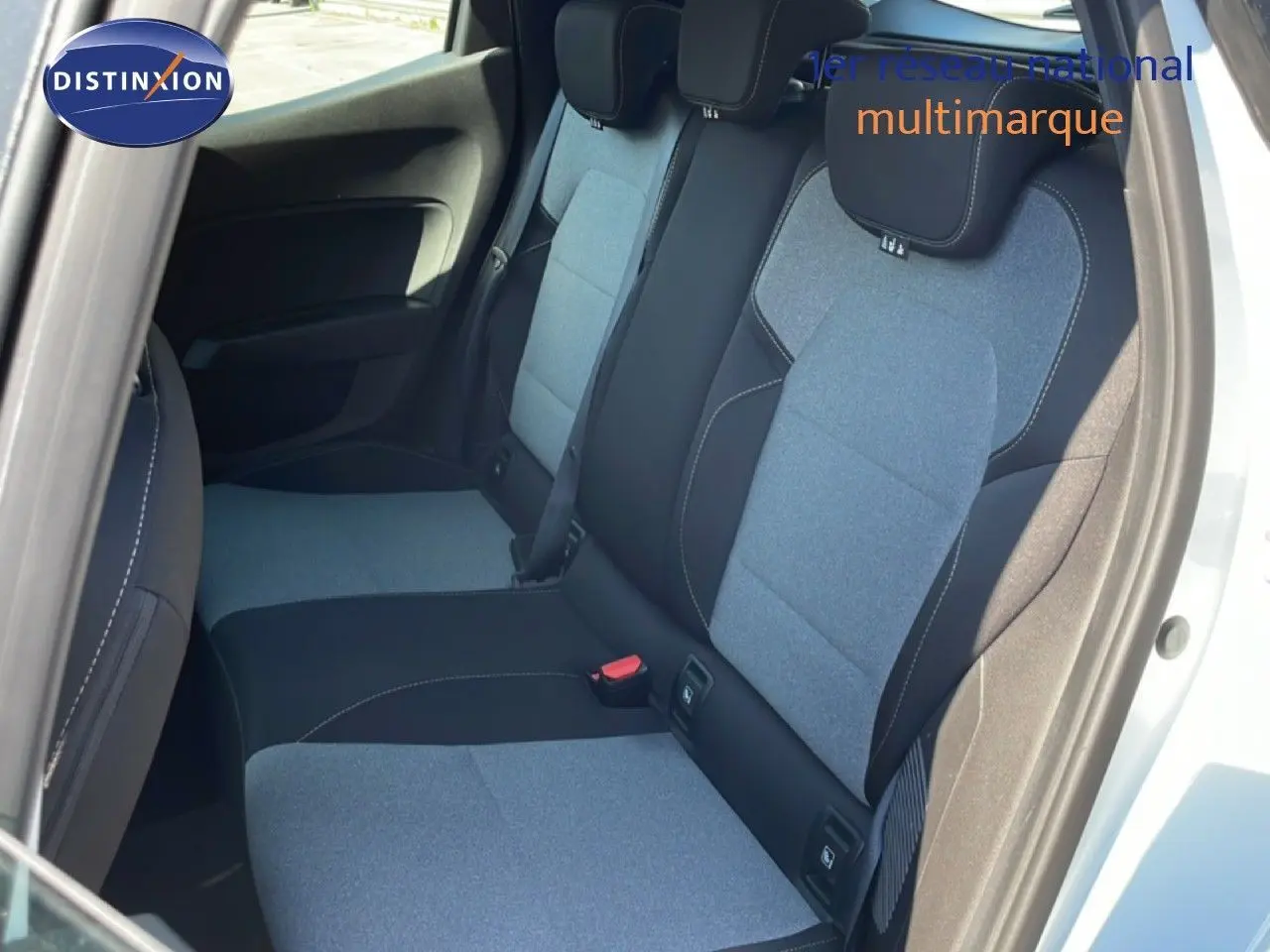 Vue intérieure côté arrière droit de la Renault Clio 2025 blanc glacier, montrant les sièges arrière en tissu bicolore gris et noir.
