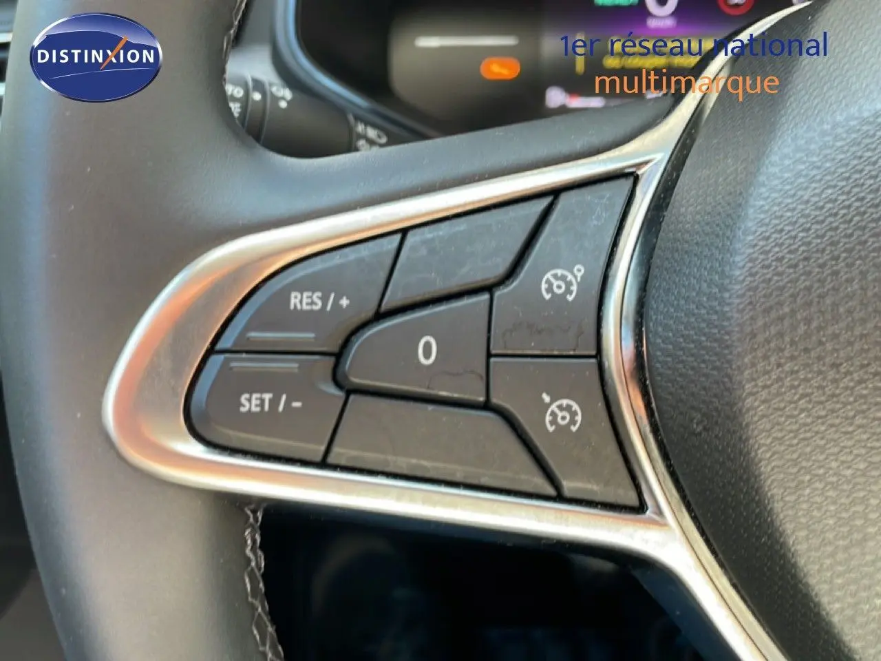 Gros plan sur les commandes de régulateur de vitesse au volant noir de la Renault Clio blanc glacier 2025.