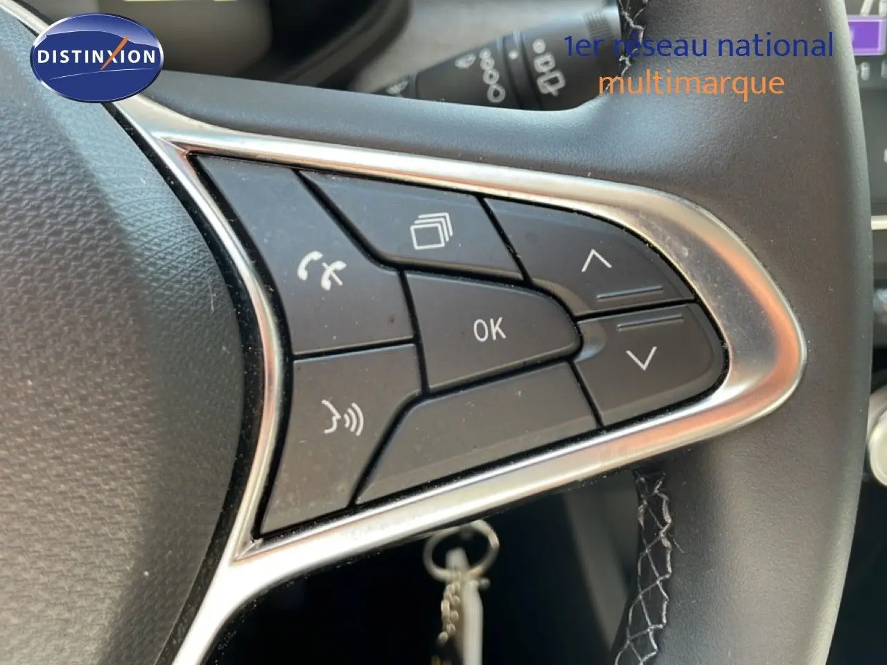 Gros plan sur les commandes multifonctions au volant en cuir noir de la Renault Clio hybride 2025.