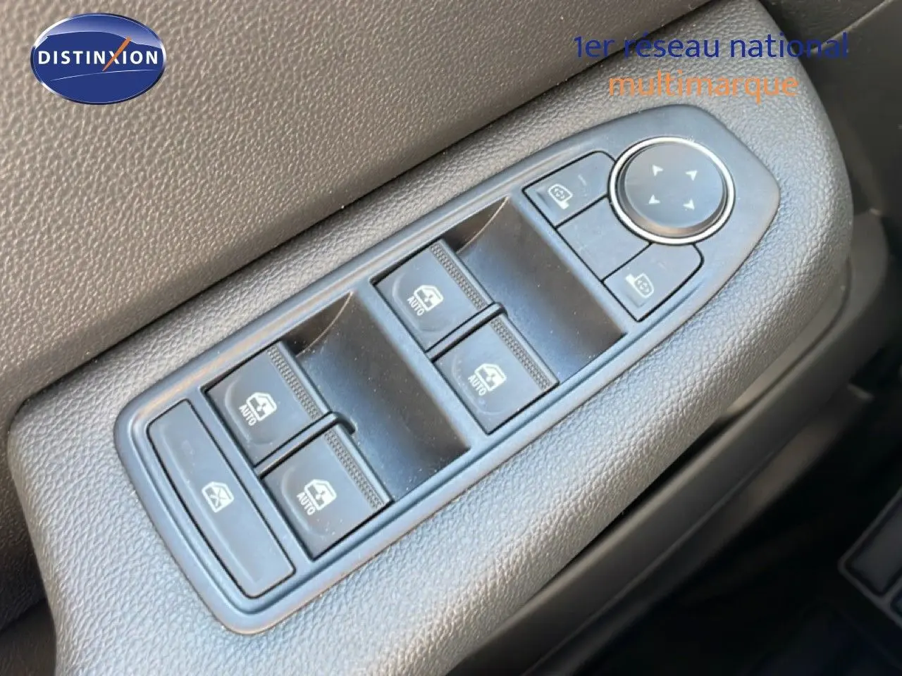 Gros plan sur les commandes de lève-vitres et rétroviseurs côté conducteur d'une Renault Clio blanche Glacier 2025.