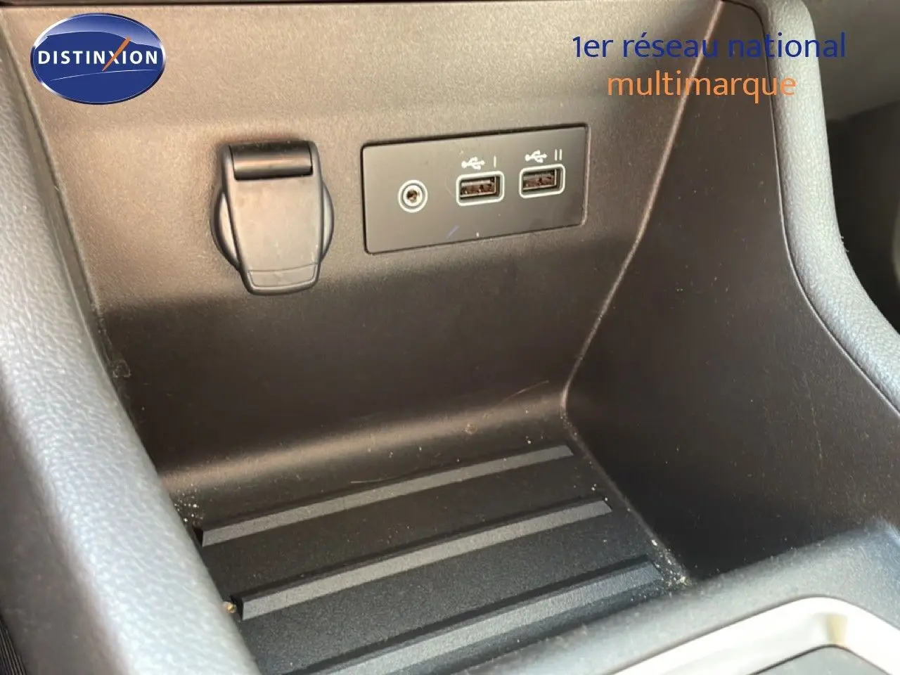 Gros plan sur la console centrale noire avec prises USB et prise 12V dans une Renault Clio Blanc Glacier.
