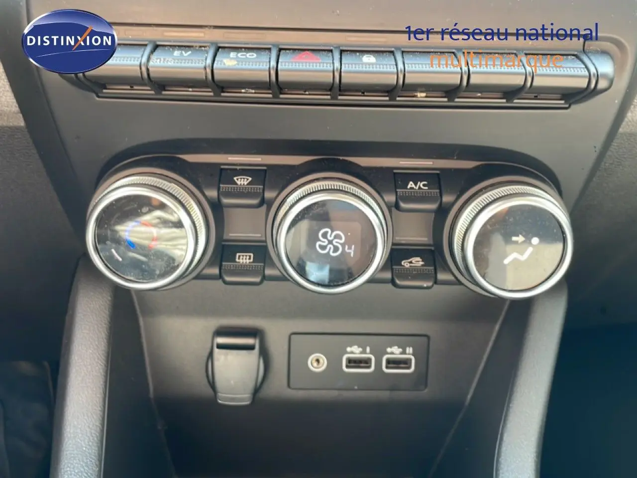 Vue rapprochée des commandes de climatisation et des ports USB du tableau de bord d'une Renault Clio blanche Glacier.