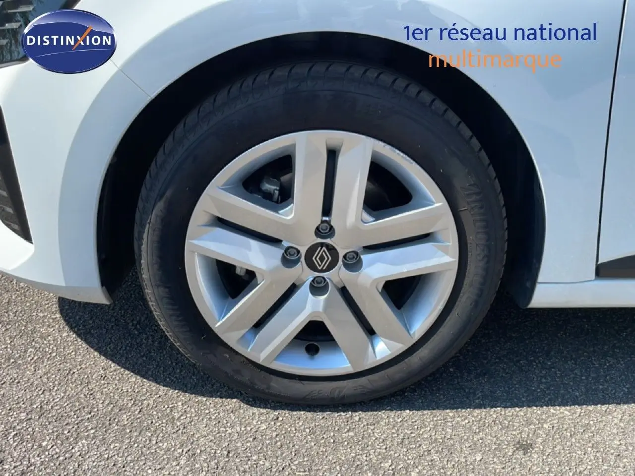 Gros plan sur la roue avant gauche blanche glacier d'une Renault Clio hybride 2025 avec jante alliage distinctive.